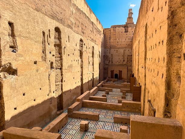 Ancient ruins of El Badi Palace in Marrakech, Morocco, showcasing intricate tile work and towering walls under a bright blue sky.
